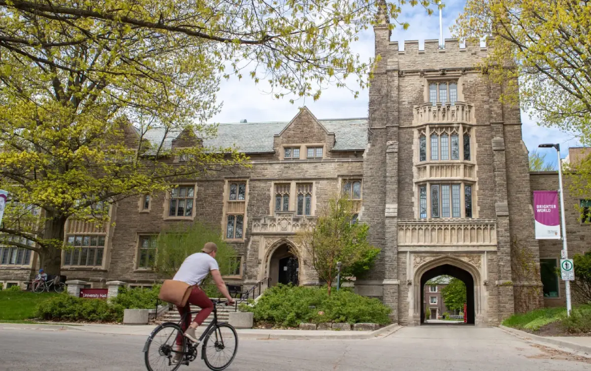 Student riding a bicycle past a university building, symbolizing campus movement and the navigation challenges explored in the UX research case study.