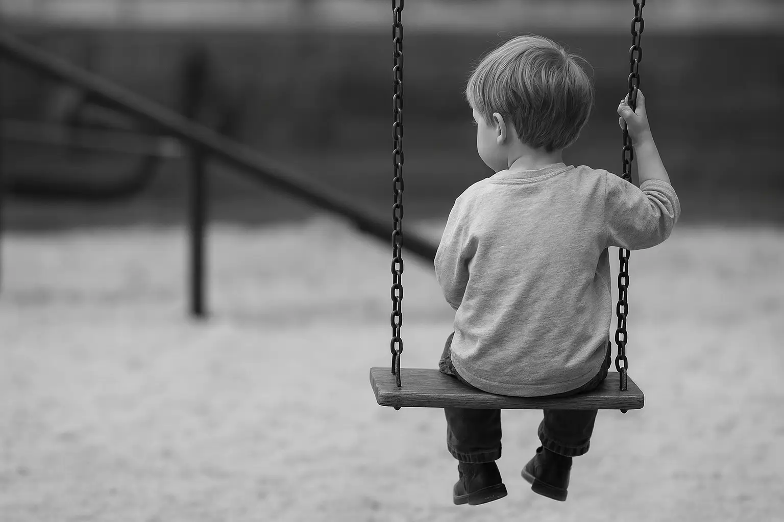 Child sitting alone on a playground swing, illustrating how standardized playgrounds can feel emotionally unengaging.